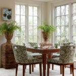 Dining room with wooden table, green floral chairs, and large wicker planters