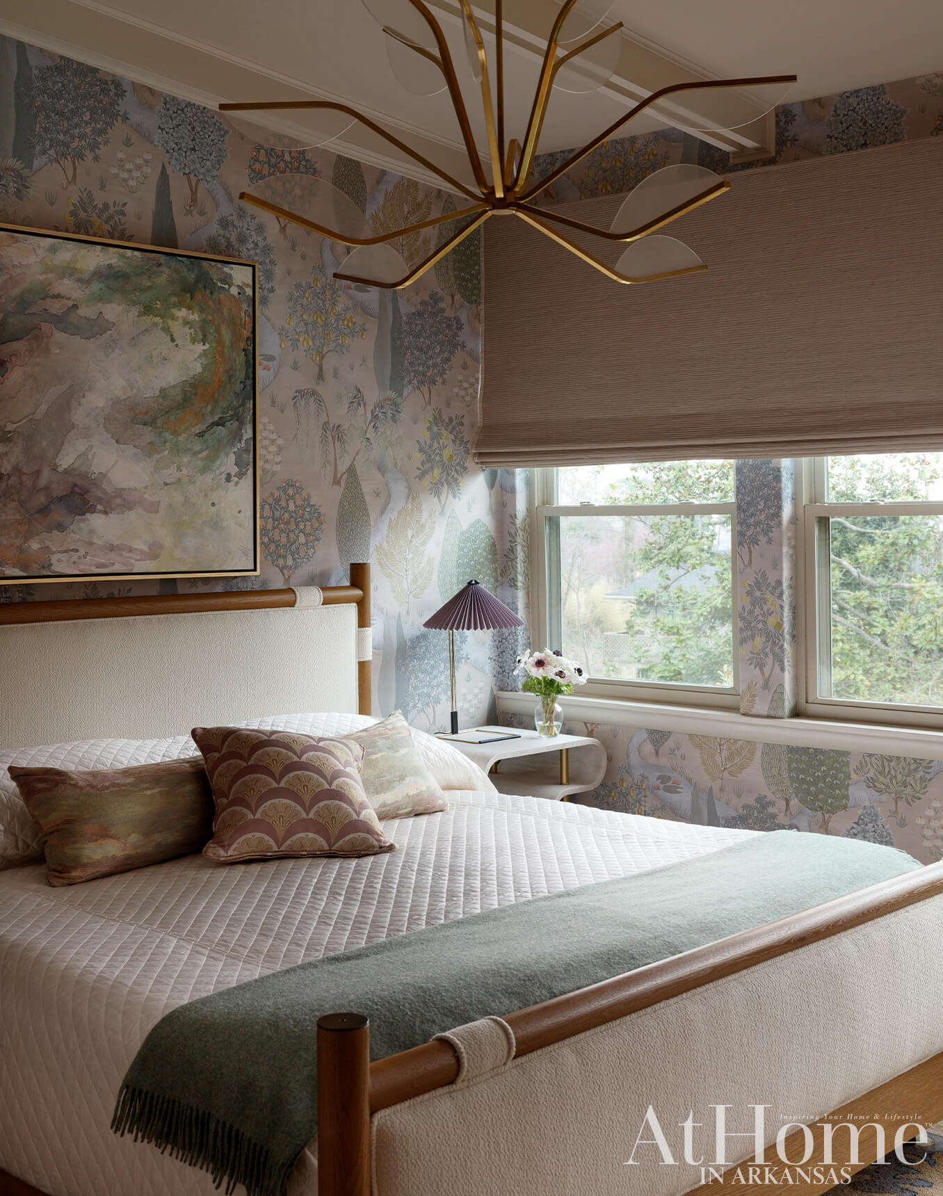 Bedroom with patterned wallpaper, quilted bed, and gold chandelier.