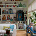 Living room with white sofa, built-in shelves filled with books and decor, and a blue distressed