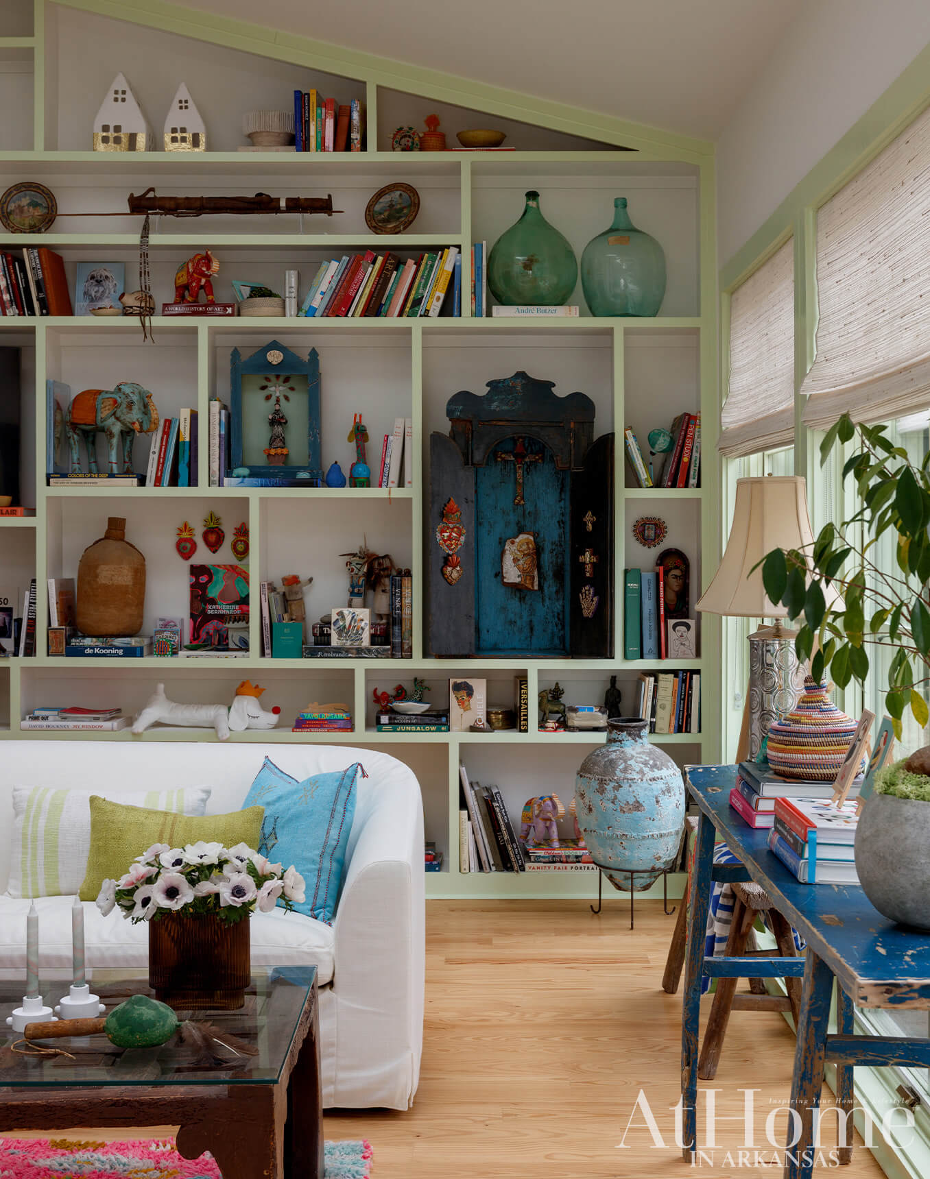 Living room with white sofa, built-in shelves filled with books and decor, and a blue distressed