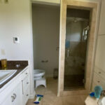 Bathroom with white vanity, granite countertop, and glass shower enclosure. Toilet visible.