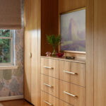 Wood dresser with brass handles, framed art, and decorative objects.