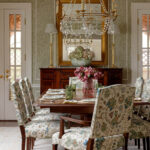 Dining room with floral upholstered chairs, dark wood table, and crystal chandelier.