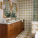 Bathroom with wood vanity, marble countertop, brass fixtures, and geometric tile.