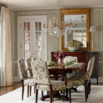 Dining room with floral upholstered chairs, dark wood table, and crystal chandelier.