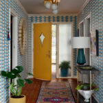 Hallway with blue triangle wallpaper, yellow door, and patterned rug.