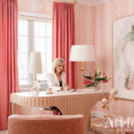 Woman at desk in pink office with floral wallpaper and abstract art