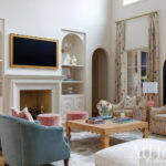 Living room with blue velvet chairs, patterned armchairs, fireplace, and burl wood coffee table.