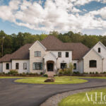 White brick house with dark windows and a circular driveway.