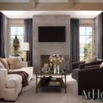 Living room with cream sofa, dark chairs, concrete fireplace, and wood beams
