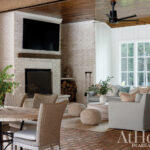 Living room with white brick fireplace, wood ceiling, and light gray sofa.