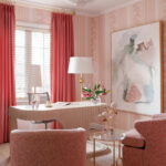 Pink office with striped wallpaper, coral curtains, a light wood desk, and abstract art.