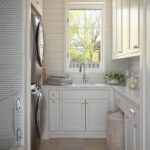 White laundry room with stacked washer/dryer, sink, white cabinets, and subway tile shower.
