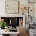 Living room with fireplace, abstract art, stacked logs, and striped armchairs.
