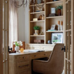Light wood desk with leather chair in home office with built-in bookshelves