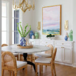 Dining room with marble table, rattan chairs, and white buffet with ginger jars.