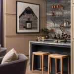 Bar area with marble countertop, tan leather stools, and artwork of a barn