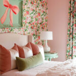Bedroom with floral wallpaper, pink walls, and a bed with striped and green pillows.