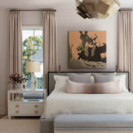 Bedroom with a king-size bed, abstract art, and a large window with pink curtains.