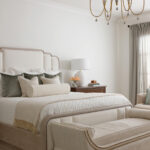 Bedroom with upholstered bed, green velvet pillows, and upholstered bench.