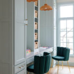 Light blue built-in desk with wicker pendant lights and teal chairs