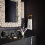 Powder room with dark textured wallpaper, stone vanity, hammered metal sink, and shell-encrusted