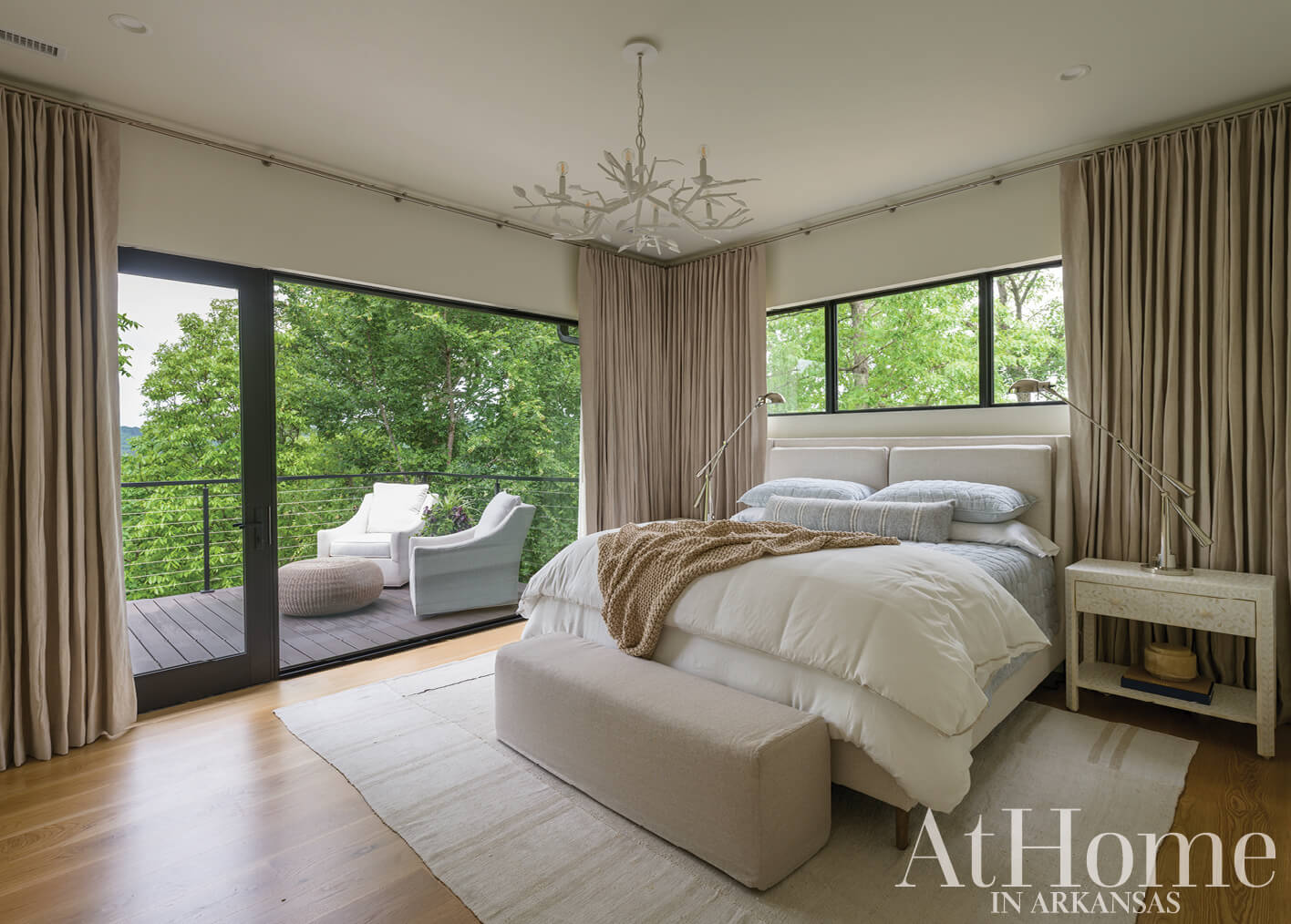 Bedroom with large windows, beige curtains, and a wooden bed.