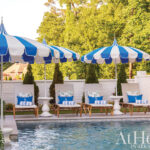 Blue and white striped umbrellas shade outdoor lounge chairs by a pool.