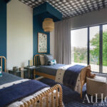 Blue bedroom with black and white checkered ceiling, twin beds, and window view.