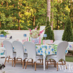 White brick wall with outdoor dining set and floral arrangement.