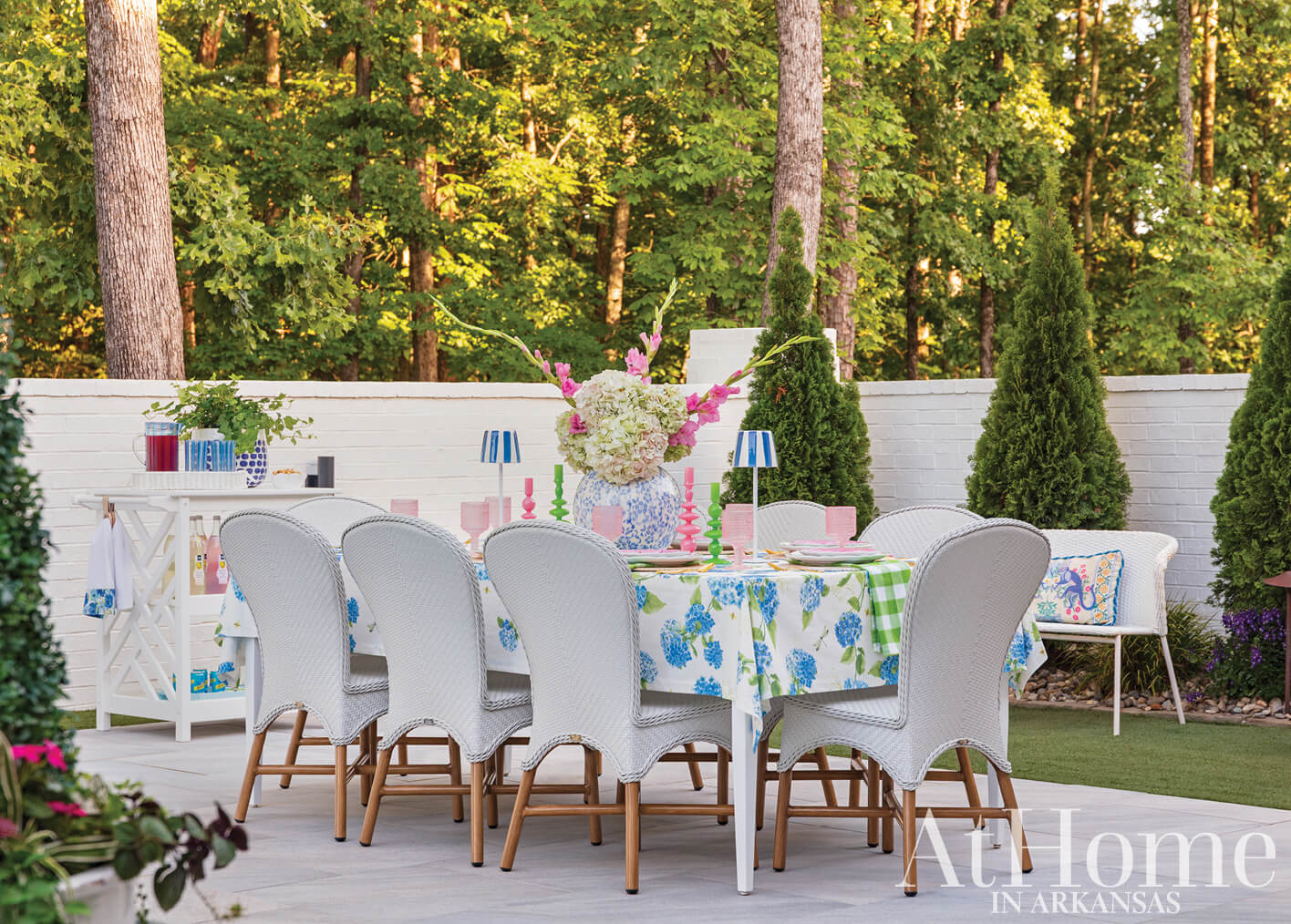 White brick wall with outdoor dining set and floral arrangement.