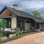 Modern home with a metal roof and stone facade, overlooking a wooded landscape.