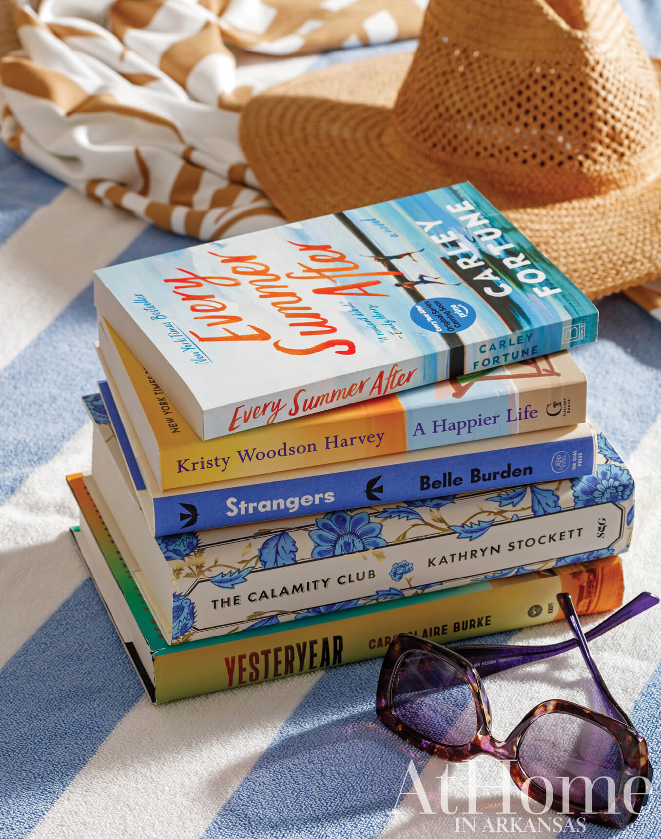 Stack of books and sunglasses on a folded towel.