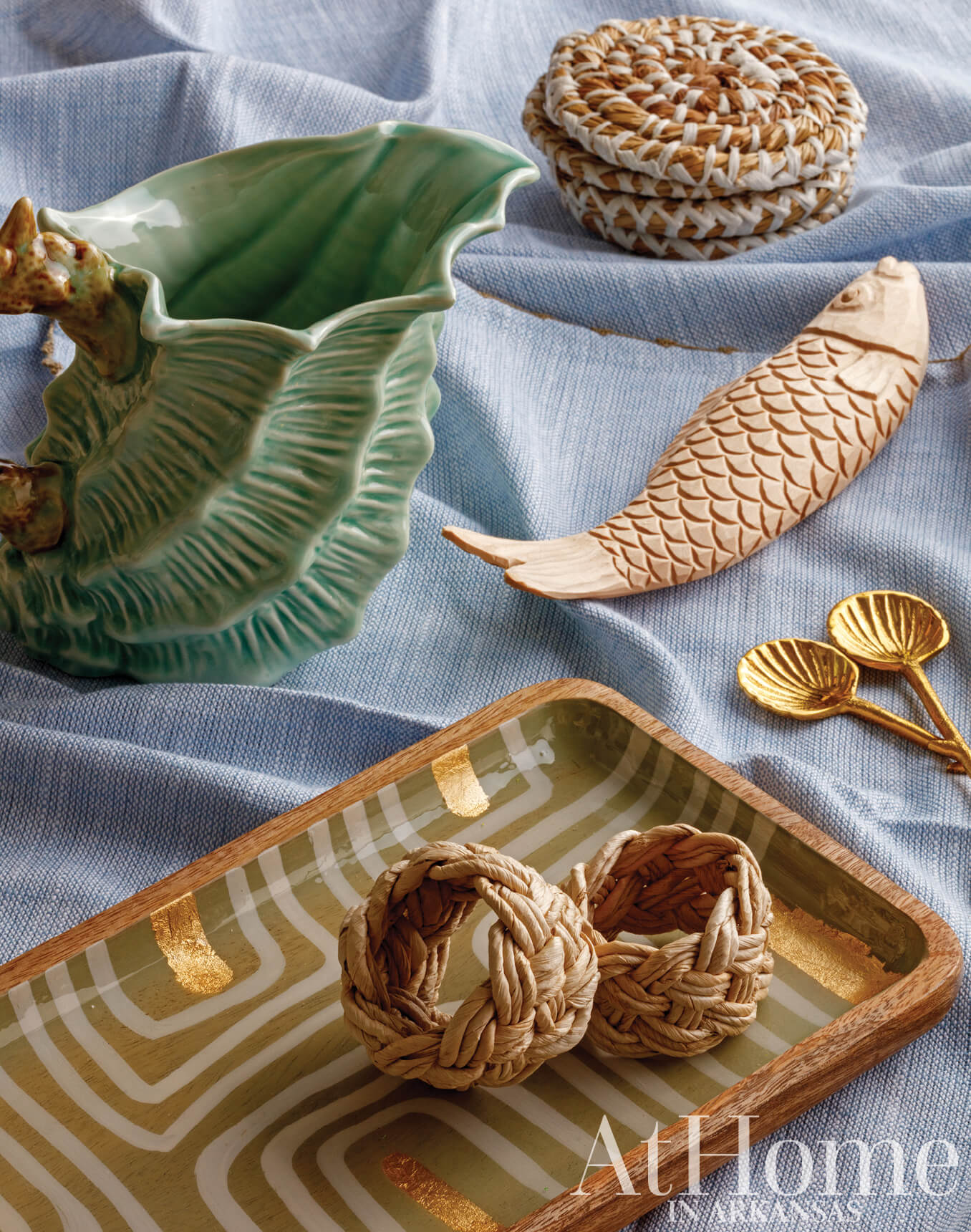 Ceramic fish and decorative objects on a blue linen surface.
