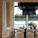 Stone archway reveals dining area with black pendant light and water view.