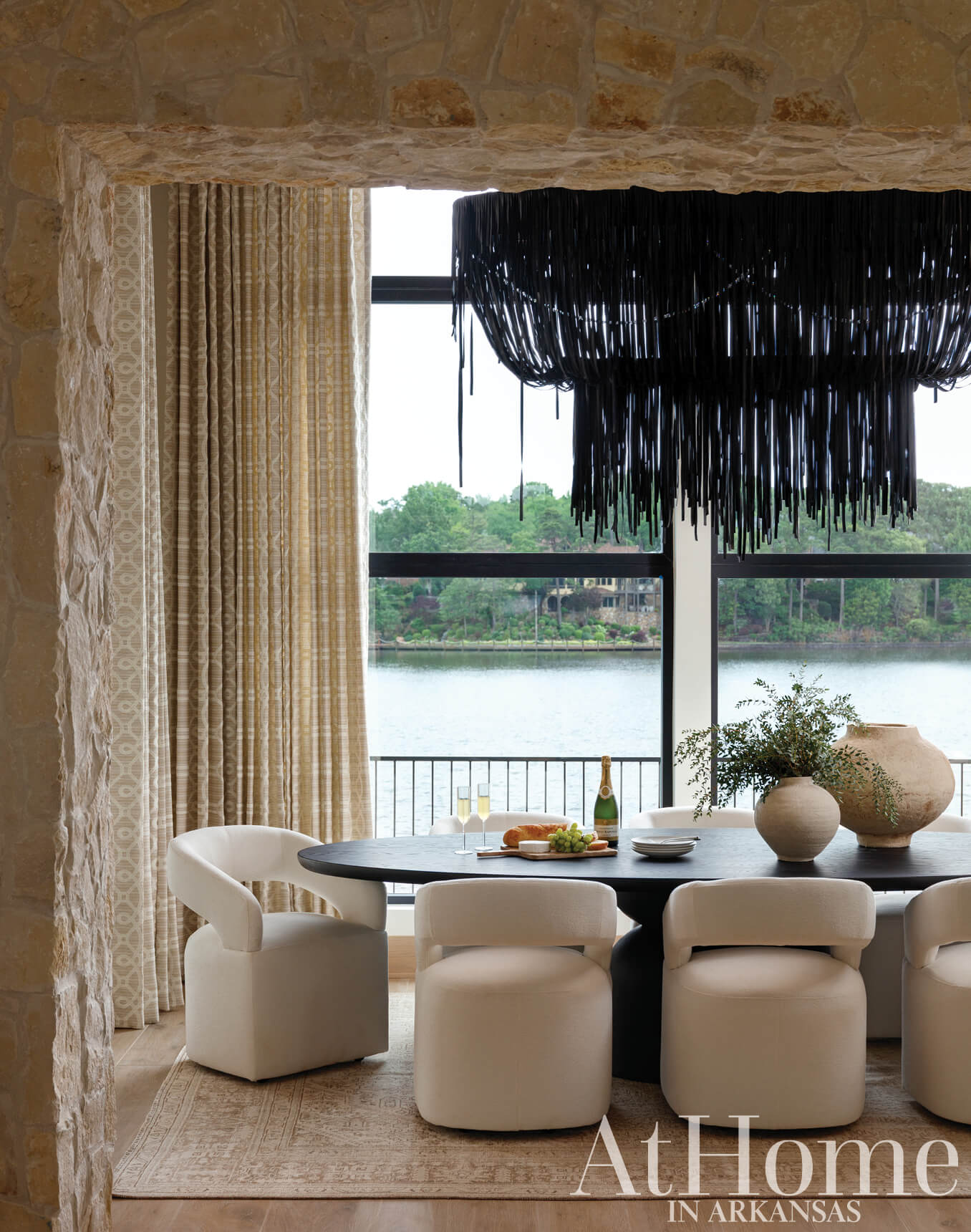 Stone archway reveals dining area with black pendant light and water view.