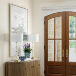 Wooden console table with lamps and artwork in entryway.