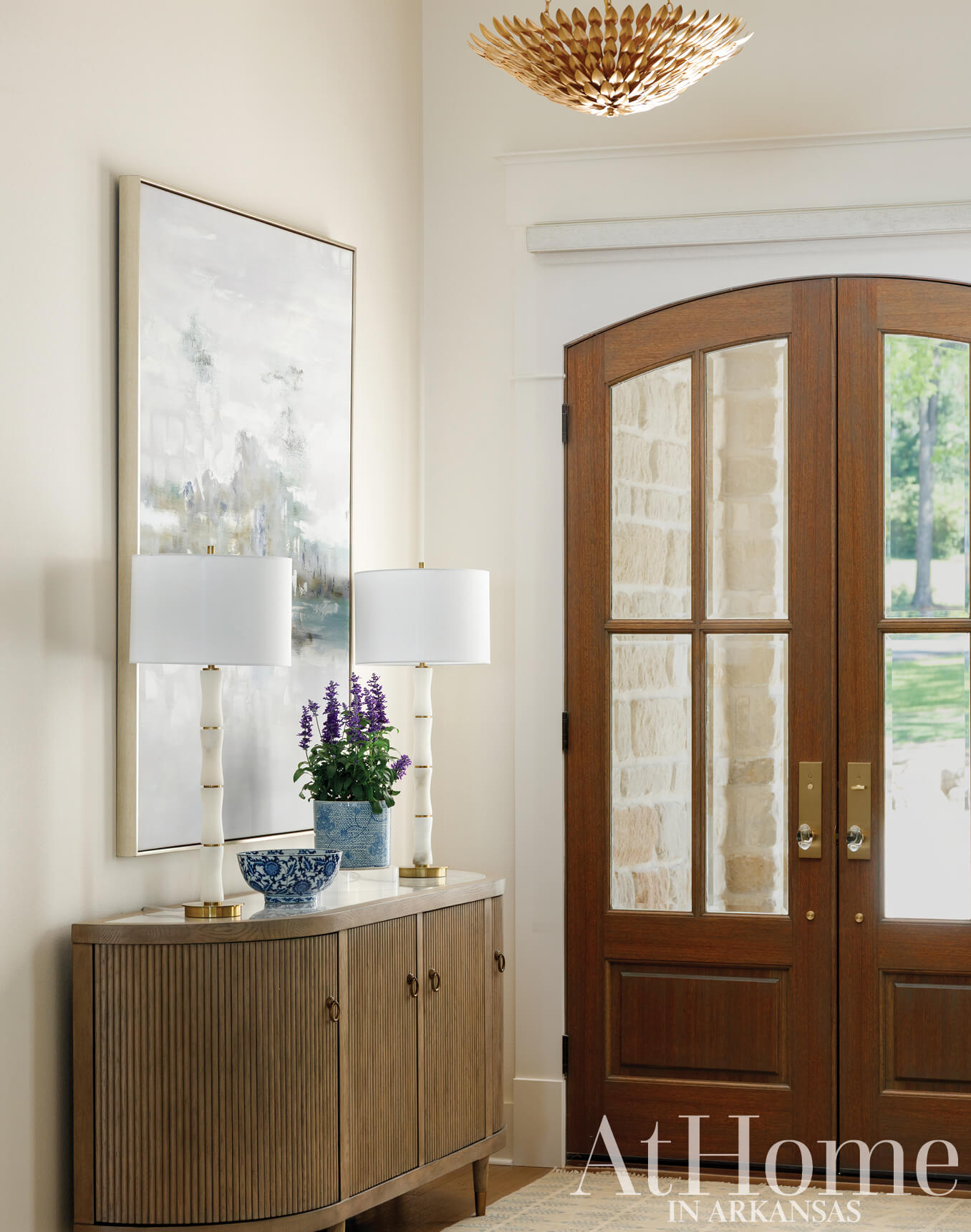 Wooden console table with lamps and artwork in entryway.