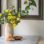 Marble countertop with floral arrangement and decorative bowl.