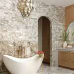 Marble wall, arched doorway, and freestanding bathtub in a luxury bathroom.