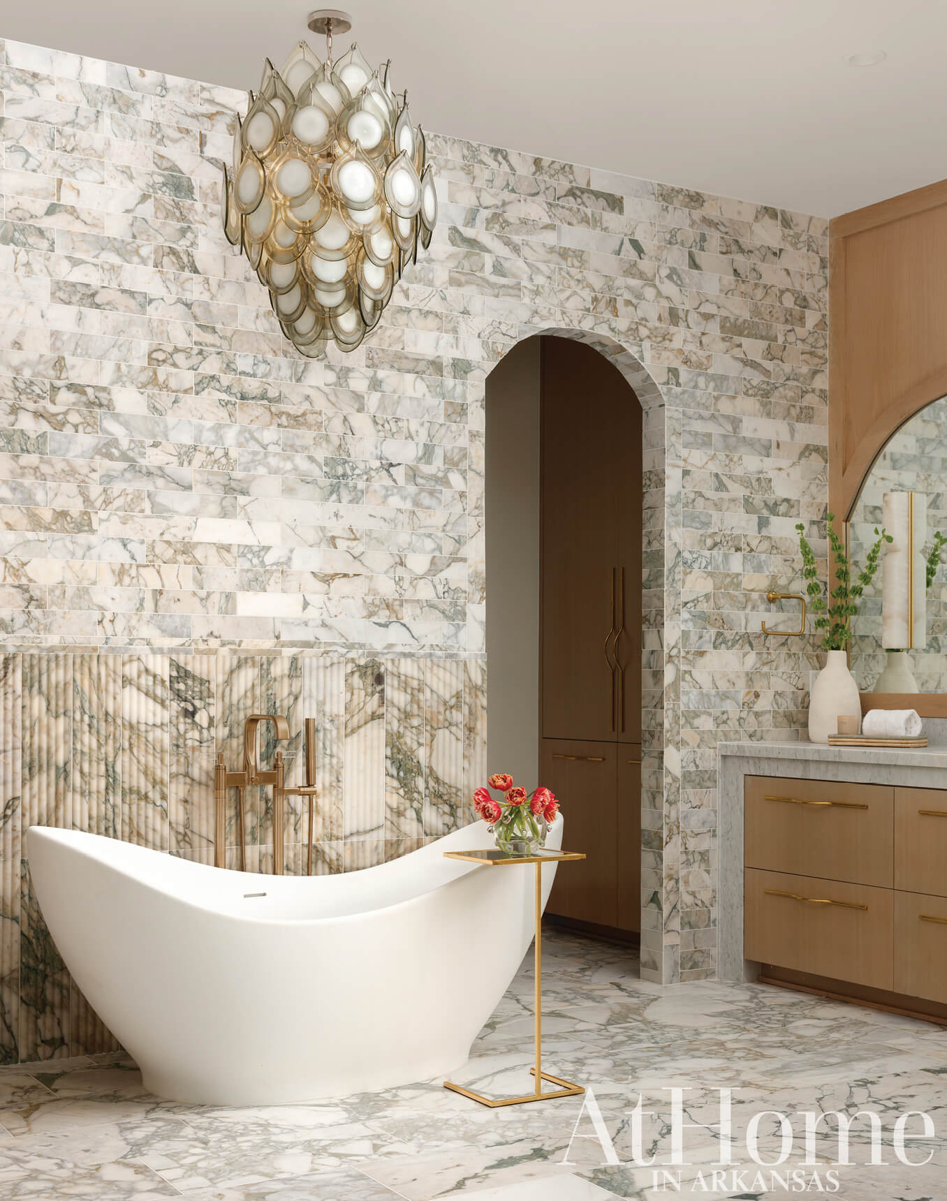 Marble wall, arched doorway, and freestanding bathtub in a luxury bathroom.