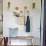 Wooden bench with coat, bag, and boots in entryway.