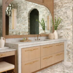 Marble and wood vanity with arched mirror and brass fixtures.