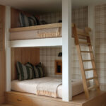 Two-tiered bunk bed with plaid wallpaper and wooden ladder.