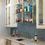 White bar with blue tile, liquor bottles, and brass accents.
