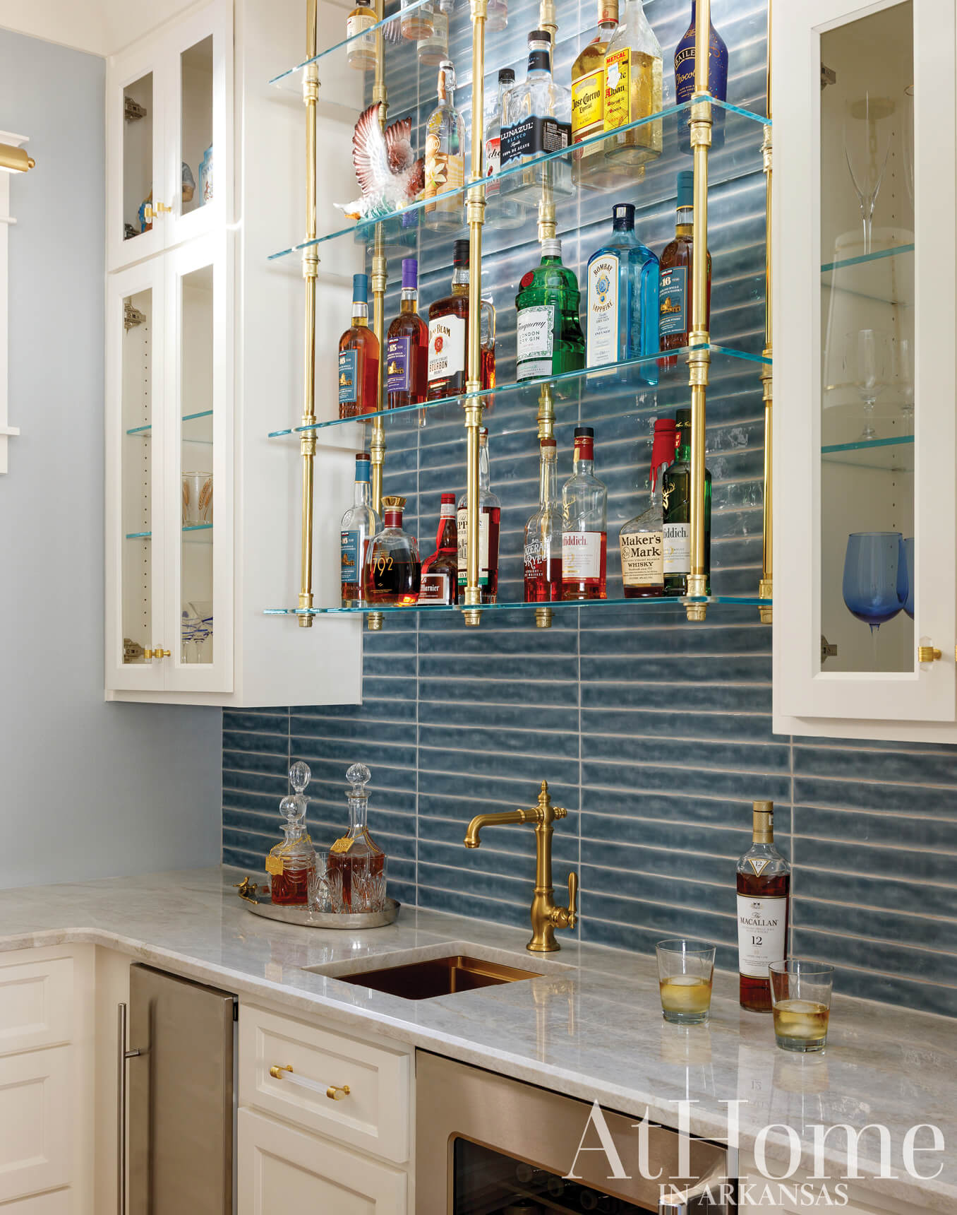 White bar with blue tile, liquor bottles, and brass accents.