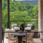 Stone patio with seating area and view of trees.