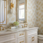 White vanity with gold fixtures in a patterned bathroom.