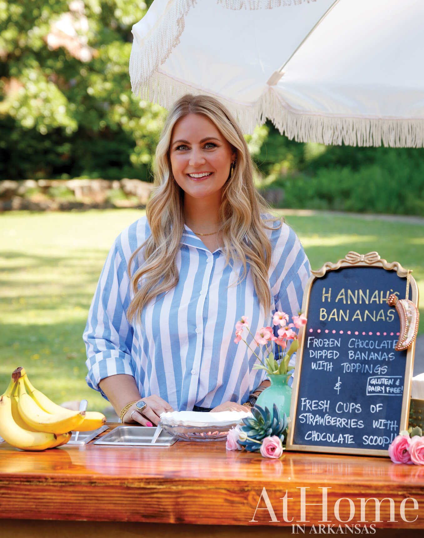 Woman smiling, holding a sign for dipped strawberries with chocolate toppings.