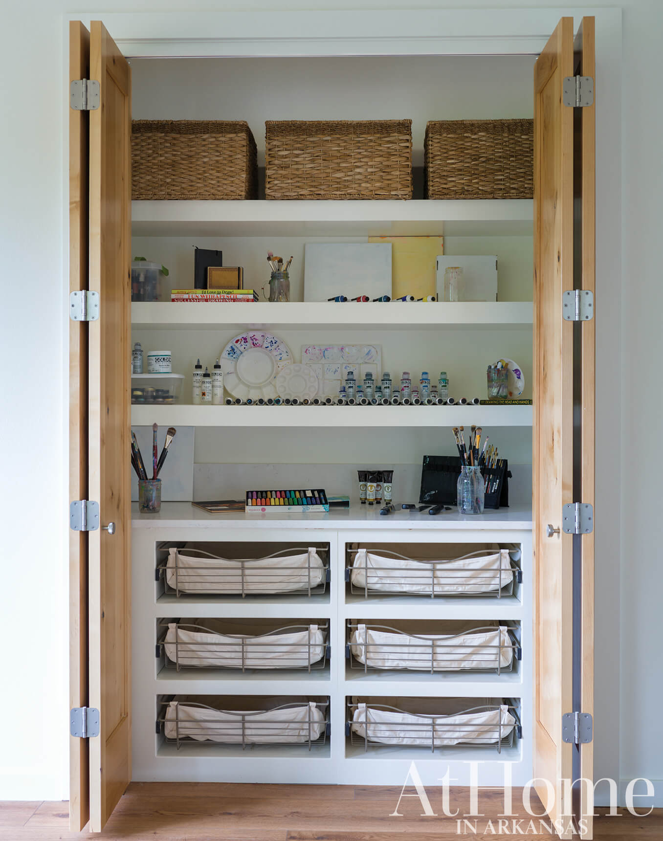 Wooden shelving unit with woven baskets and art supplies.